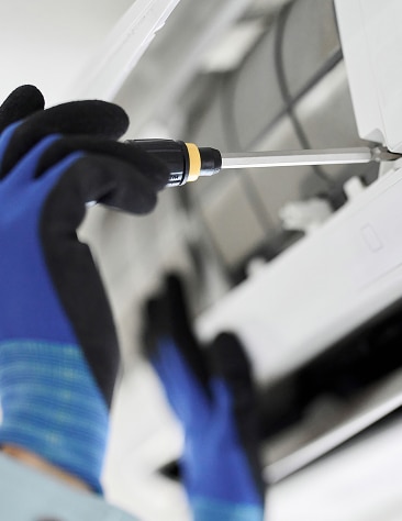 Climatiseur mural et salon moderne ensoleillé Climatiseur mural blanc moderne au-dessus d'un canapé gris clair, avec la lumière du soleil filtrant par une grande fenêtre. Ambiance intérieure lumineuse.