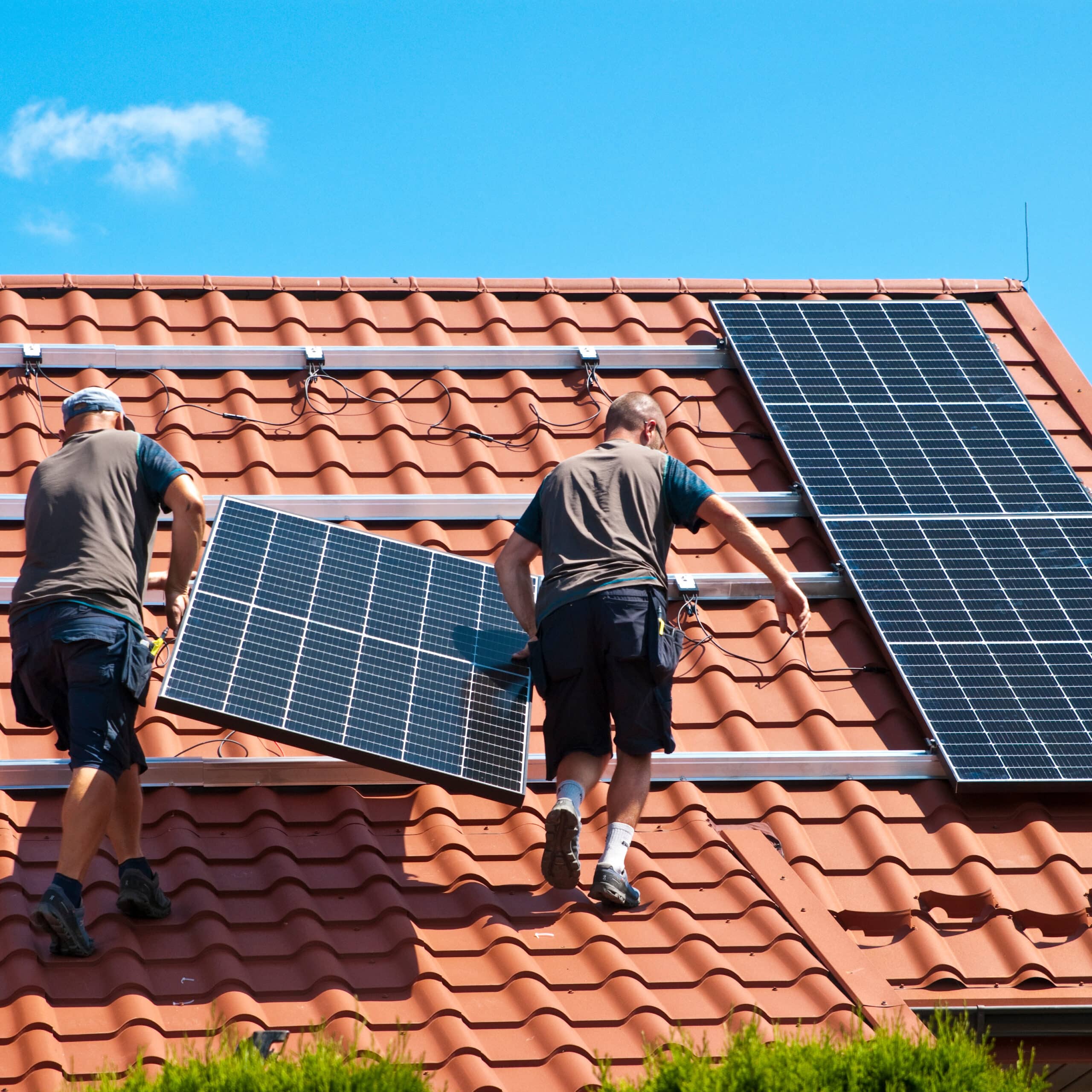 Climatiseur mural blanc moderne au-dessus d'un canapé gris clair, avec la lumière du soleil filtrant par une grande fenêtre. Ambiance intérieure lumineuse.